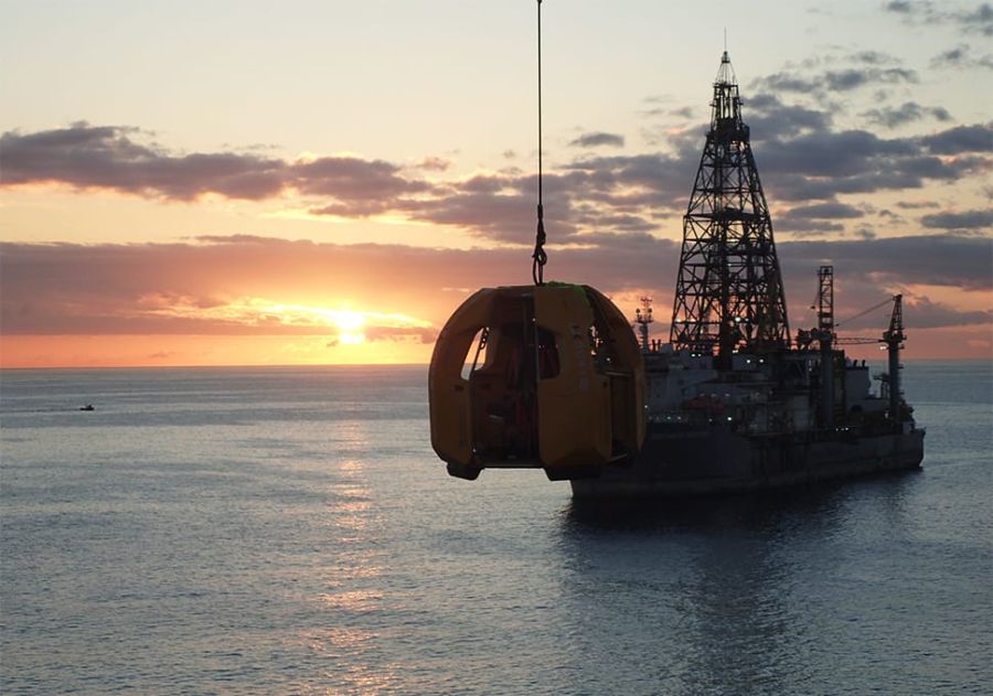 The sun sets behind a Stena Drilling oil rig and the Reflex Marine FROG XT suspended in the air.